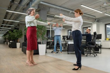 Four office workers warm up during a break. Employees do fitness exercises at the workplace