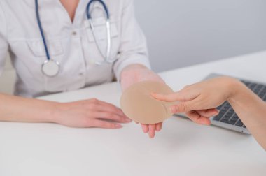 Caucasian woman and plastic surgeon touching and choosing breast implants