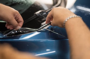 Araba servisindeki usta koruyucu kesiciyi kesiyor.