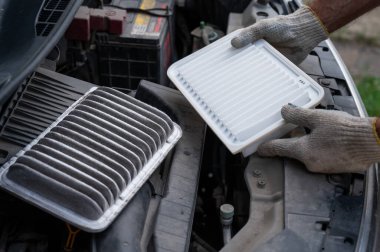 Araba motorundaki hava filtresini değiştiriyor.