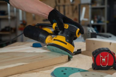 Atölyede çim biçme makinesi kullanan bir adam. Bir marangozun ellerine yakın çekim