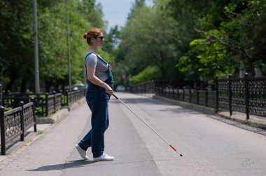 Kör hamile bir kadın, bir değneğin yardımıyla karşıdan karşıya geçiyor.