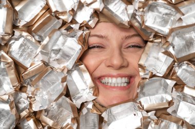 The face of a Caucasian woman surrounded by candy wrappers