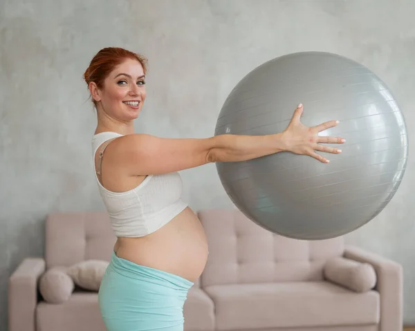 Zwangere Roodharige Vrouw Doet Armoefeningen Met Fitbal Thuis — Stockfoto