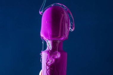Özel kayganlaştırıcı mavi arka planda mor bir vibratöre dökülür. Boşluğu kopyala