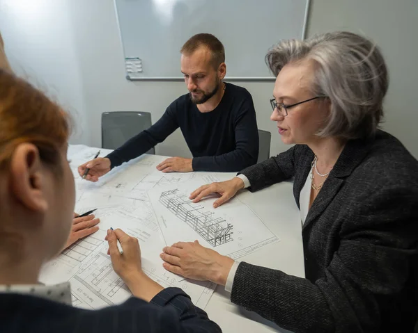 Dört iş adamı bir masanın etrafında oturmuş planları tartışıyor. Bir toplantıda tasarımcılar.