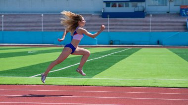 Genç beyaz kadın açık hava stadyumunda koşuya çıktı.