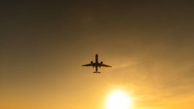 Gün batımında uçan bir uçağın alt görüntüsü.