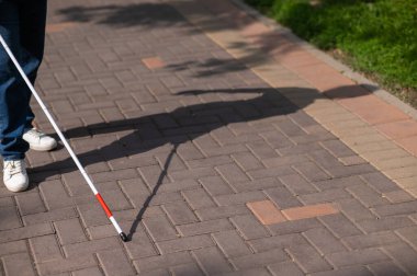 Yüzü olmayan kör bir kadın bastonuyla sokakta yürüyor.