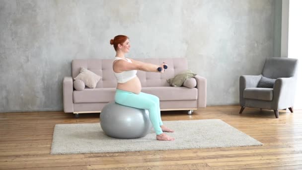 孕妇坐在健身球上用哑铃做运动 — 图库视频影像
