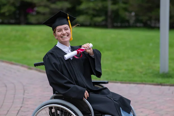 stock image Happy caucasian woman in a wheelchair holding her diploma outdoors