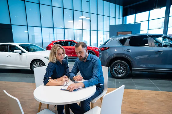 Caucasian couple signs a car purchase agreement in a car dealership