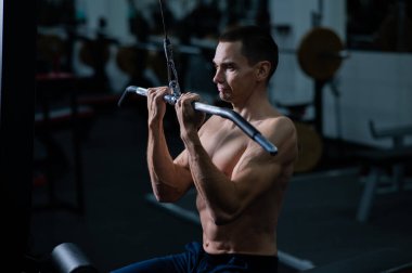 A man does a chest pulldown in the gym