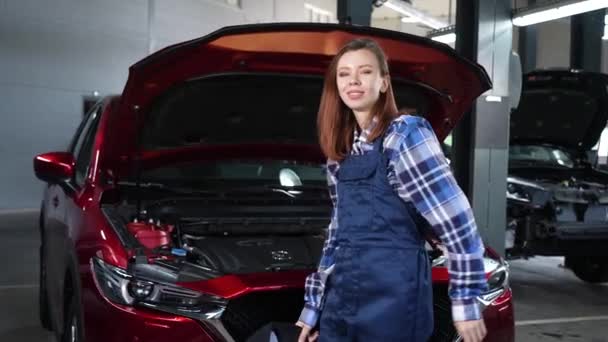 Μια Γυναίκα Μηχανικός Αυτοκινήτων Στέκεται Στο Ανοικτό Καπό Ενός Αυτοκινήτου — Αρχείο Βίντεο