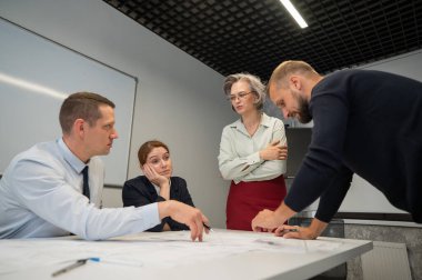 The female boss evaluates the work of subordinates. Designers engineers at a meeting