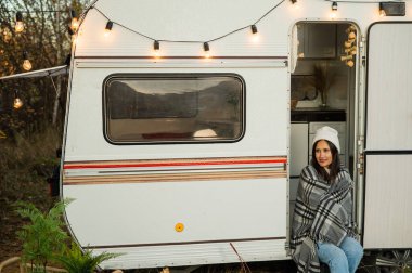 Beyaz kadın sıcak bir sonbahar gününde minibüste oturuyor. Bir karavanla seyahat et.