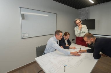 The female boss evaluates the work of subordinates. Designers engineers at a meeting
