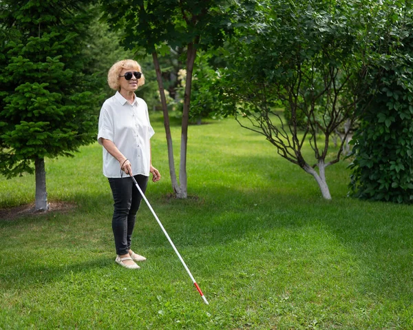 Elderly blind woman walking in the park
