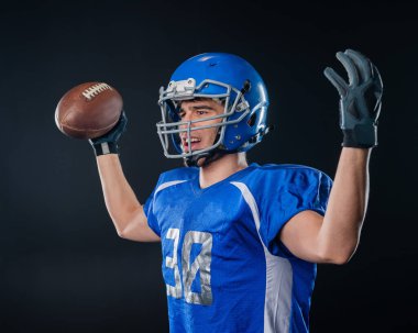 Siyah arka planda Amerikan futbolu için mavi üniformalı bir adamın portresi.