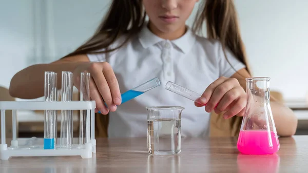 stock image A schoolgirl conducts experiments in a chemistry lesson. Girl pouring colored liquids from a beaker