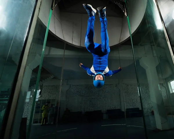 stock image A man in overalls and a protective helmet enjoys flying in a wind tunnel. Free fall simulator.