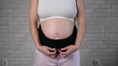 Hamile bir kadın iki parçalı siyah bandajı çıkarır. Kesik göbek