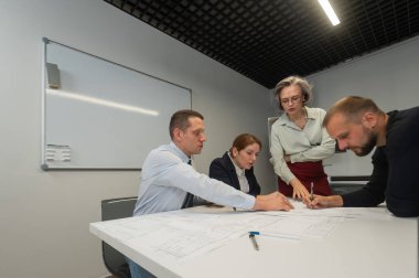 The female boss evaluates the work of subordinates. Designers engineers at a meeting