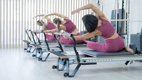 Three Asian Women Pink Sportswear Doing Side Bends Reformer Machine — Foto de Stock