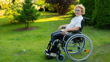 Happy elderly woman sitting in a wheelchair on a walk outdoors