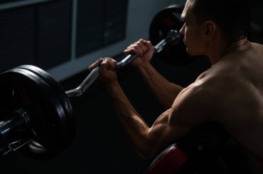 Man doing EZ barbell bicep exercises on Scott bench