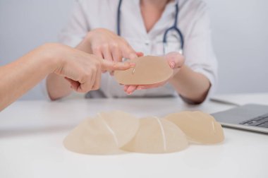 Caucasian woman and plastic surgeon touching and choosing breast implants