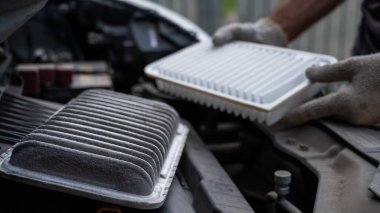 Araba motorundaki hava filtresini değiştiriyor.