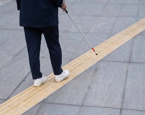 用手杖在触觉瓷砖上行走的盲眼女商人的腿特写 — 图库照片