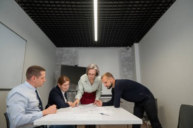 The female boss evaluates the work of subordinates. Designers engineers at a meeting