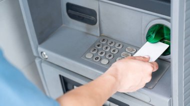 Yüzü olmayan bir kadın ATM 'ye kredi kartı sokuyor. ATM makinesiyle bir kadının ellerini yakın plan çek.