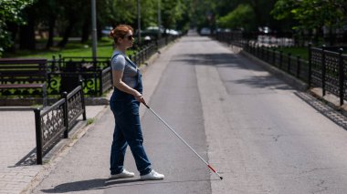 Kör hamile bir kadın, bir değneğin yardımıyla karşıdan karşıya geçiyor.