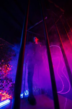 Çelik parmaklıkların arkasındaki neon stüdyodaki beyaz kadın.