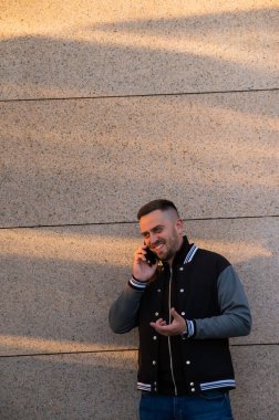 Sakallı adam gün batımında dışarıda akıllı telefon kullanıyor.