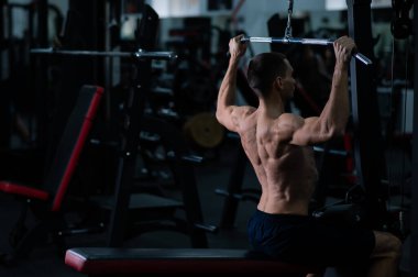 A man does a chest pulldown in the gym