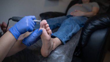 Güzellik salonunda hırdavat pedikür yapan hamile bir kadın.