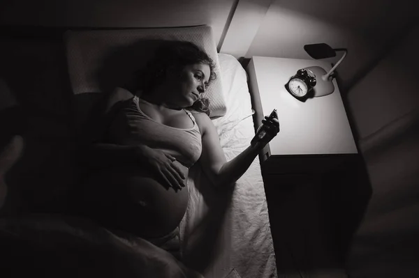 Μια Έγκυος Γυναίκα Ξαπλώνει Στο Κρεβάτι Και Χρησιμοποιεί Ένα Smartphone — Φωτογραφία Αρχείου