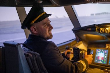 Uçuş simülatöründe otururken gülümseyen beyaz sakallı adam. Pilot kokpitte.