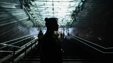 Merdivenlerin yanındaki metroda poz veren Asyalı genç bir kadının portresi.