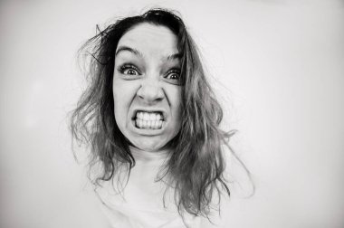 Beyaz arka planda deli gömleği giymiş deli bir kadının yakın plan portresi. Tek Renkli