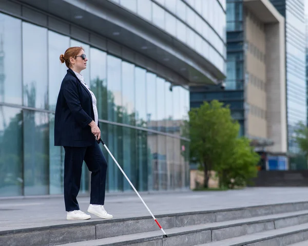 stock image Blind business woman descending stairs with a tactile cane from a business center