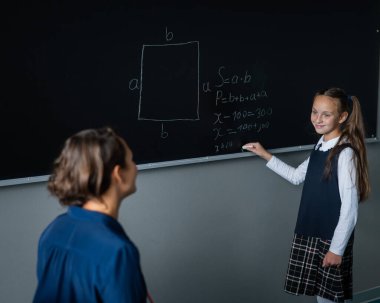 Kafkasyalı küçük kız tahtadaki kadın öğretmenin sorusuna cevap veriyor.