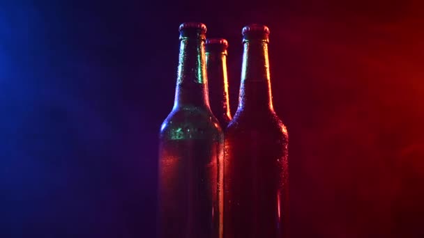 Três Garrafas Cerveja Girando Uma Névoa Azul Rosa — Vídeo de Stock