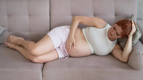 Λευκή Έγκυος Γυναίκα Ξαπλώνει Στον Καναπέ Και Υποφέρει Από Πόνο — Φωτογραφία Αρχείου