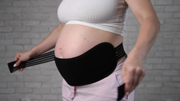 Una Mujer Embarazada Pone Vendaje Negro Dos Piezas Vientre Recortado — Vídeo de stock