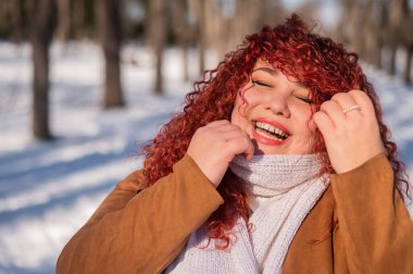 Portrait of a smiling chubby red-haired woman on a walk in winter